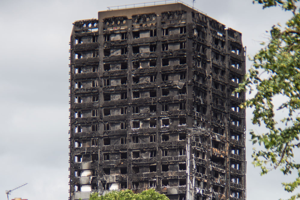 A tall, charred building with blackened walls and broken windows, showing signs of extensive fire damage.